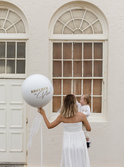 Mother and Son at Bar Beach Surf House holding a white Gender Reveal balloon with custom made "Brother or Sister?" message on the balloon. Made by Newcastle Dried Flower Co.